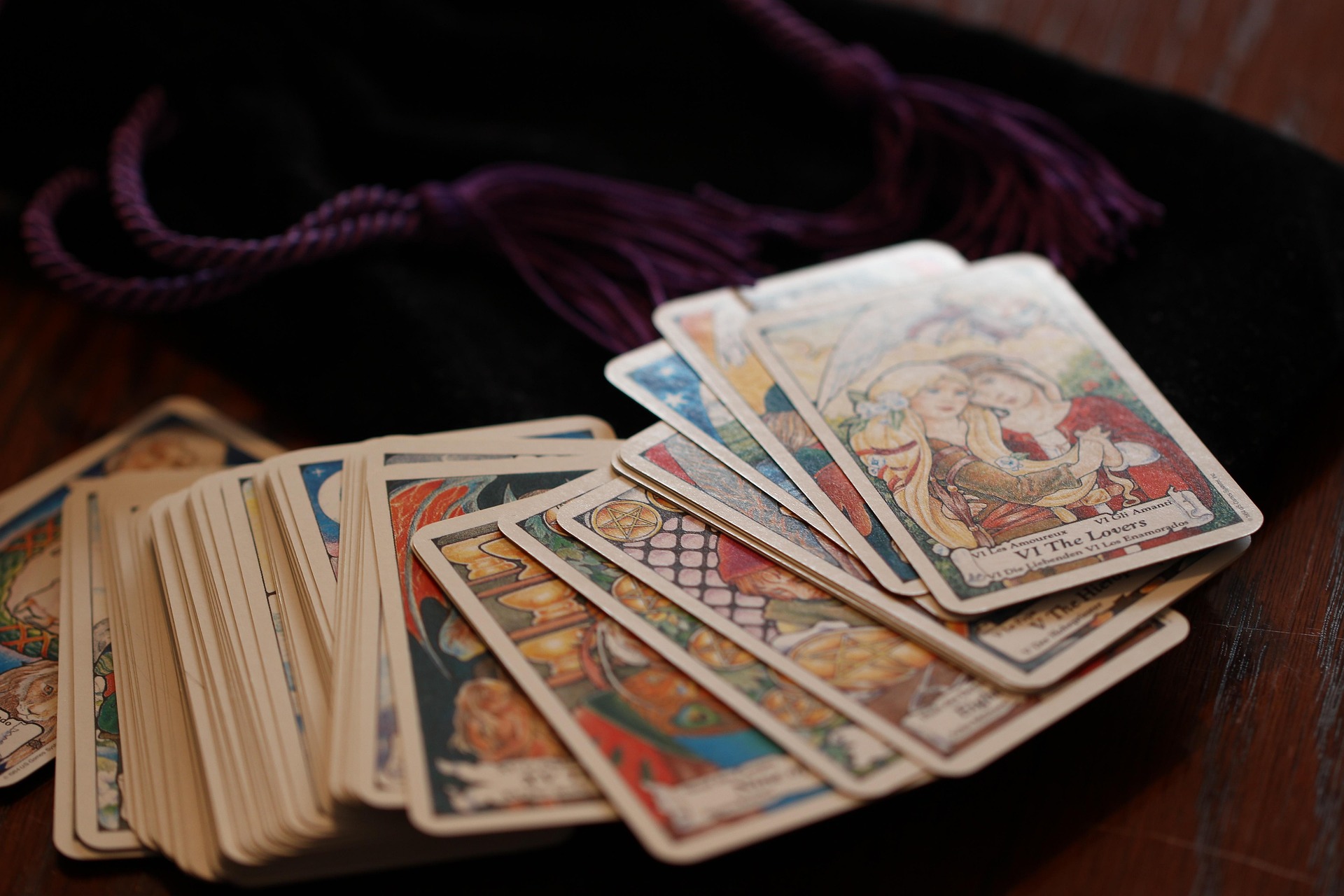 A spread of illustrated tarot cards, The Lovers face up, laid across a dark velvet cloth